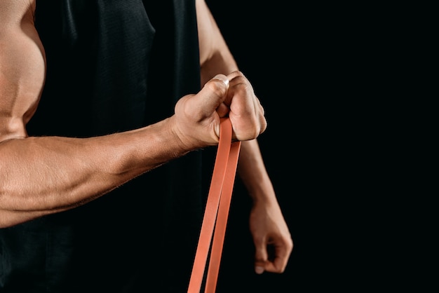 Foto vista parcial del entrenamiento culturista muscular con banda de resistencia aislada en negro