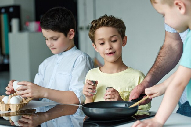 vista parcial de la familia cocinando huevos para desayunar juntos en la cocina de casa