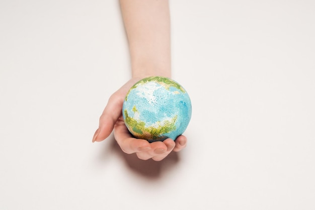 Foto vista parcial de la mano femenina con modelo de la tierra en fondo blanco concepto de calentamiento global