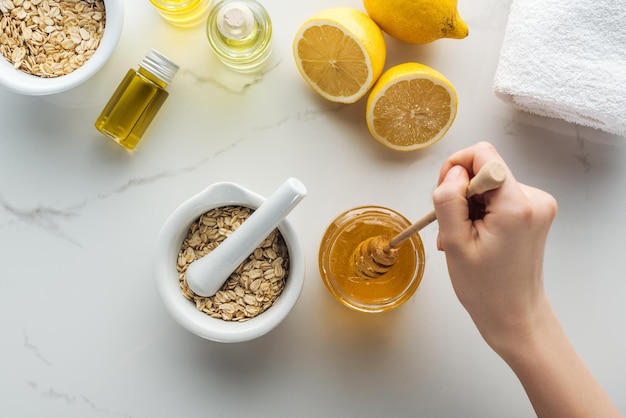 Foto vista parcial de la mano femenina con palito de miel pounder con copos de avena limones y diferentes naturales