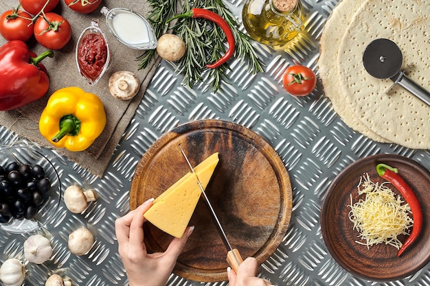 Vista parcial de la mujer cortando queso mientras cocina pizza italiana casera