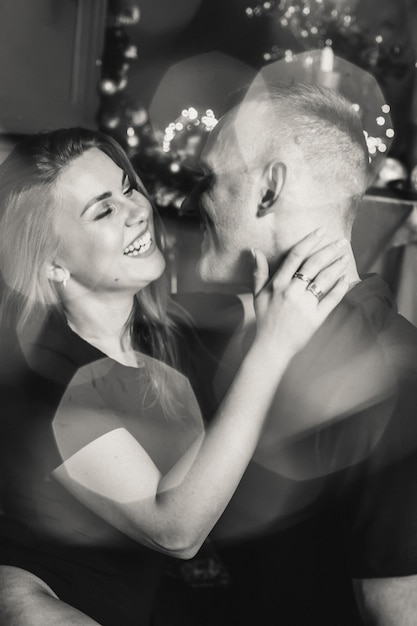 Vista de una pareja romántica apasionada que pasa tiempo antes de Año Nuevo en casa con guirnaldas Mujer joven y hombre guapo abrazo beso Navidad