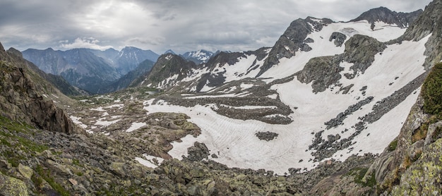 Vista desde el paso de montaña al valle, piedras y nieve.