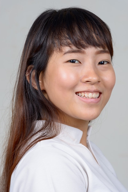 Vista de perfil de cerca de feliz joven asiática mirando a la cámara