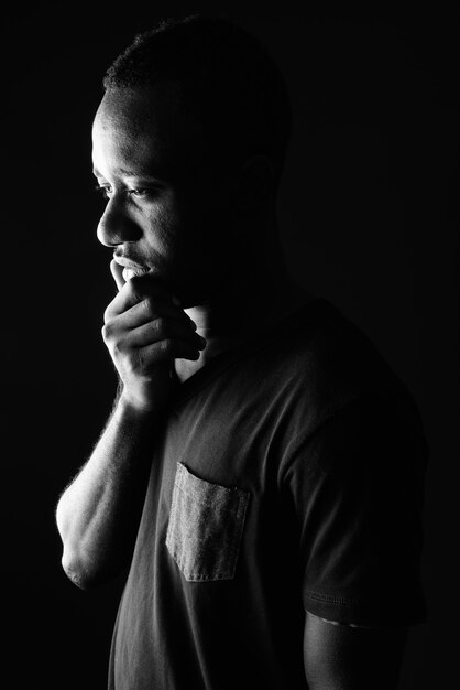 Vista de perfil de hombre africano joven triste pensando en blanco y negro