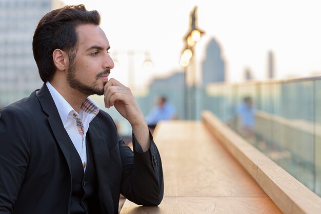 Vista de perfil del joven empresario indio guapo pensando en el restaurante de la azotea en