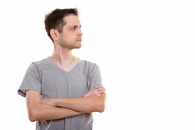 Vista de perfil del joven enojado con los brazos cruzados