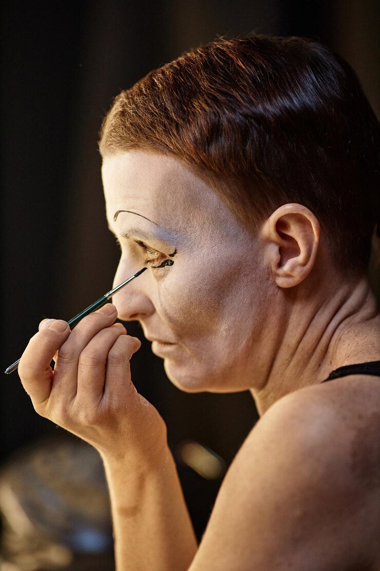 Foto vista del perfil de una mujer adulta haciendo maquillaje de mimo