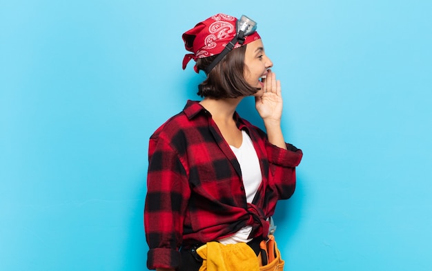 Vista de perfil de mujer latina joven, luciendo feliz y emocionada, gritando y llamando para copiar espacio en el lateral