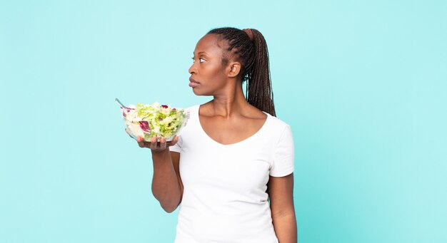 En la vista de perfil pensando, imaginando o soñando despierto y sosteniendo una ensalada