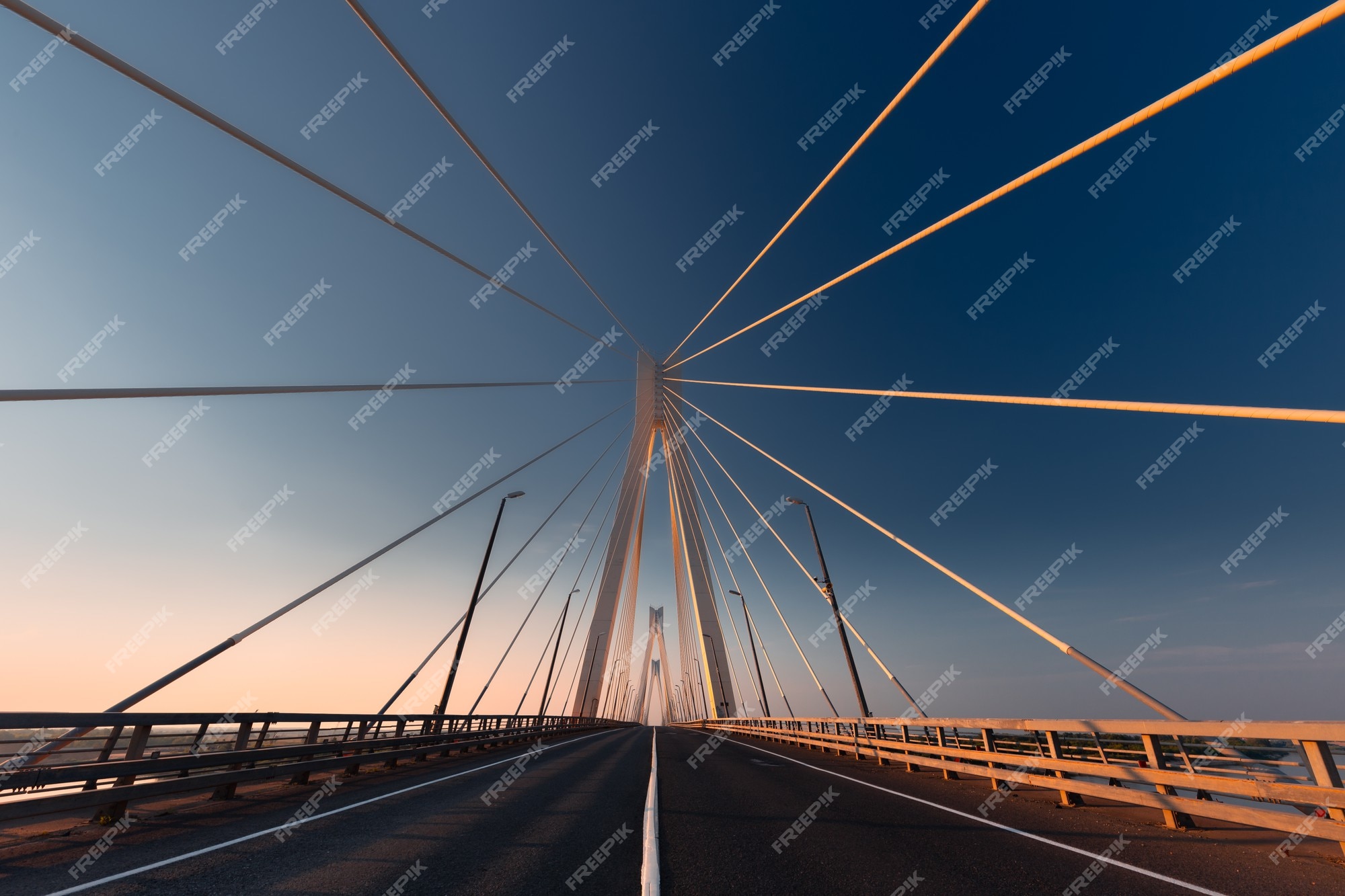 Vista en perspectiva lineal de puente colgante atirantado blanco en la luz dorada del sol naciente tomada desde el nivel suelo en horizontal (paisaje) | Foto Premium