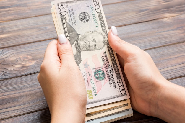 Vista en perspectiva de la mano femenina dando billetes de cien dólares. Concepto de caridad y donación con espacio de copia
