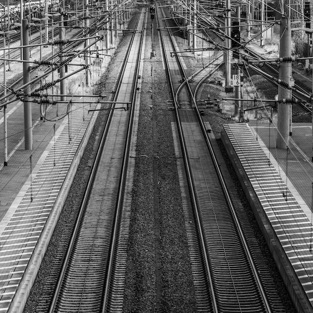 Foto vista en perspectiva de las vías ferroviarias con líneas aéreas junto a una plataforma