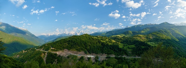 Vista de los picos de las montañas. Carretera de montaña y montañas con nubes.