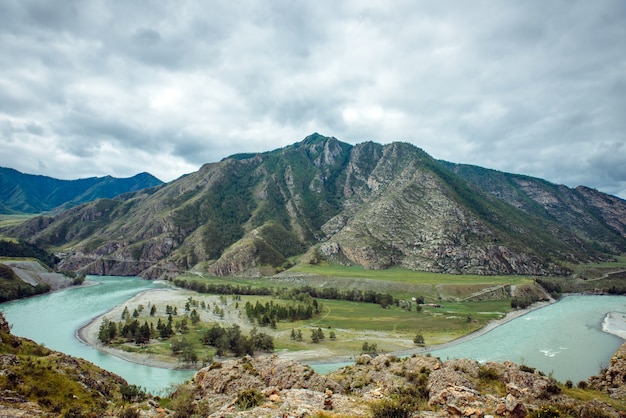 Vista pintoresca sobre la confluencia de dos ríos de montaña. El río Katun y el río Chuya contra las montañas de Altai, Rusia. Paisaje de montaña en un día nublado de verano