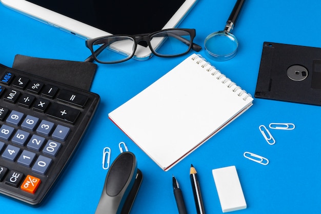 Vista plana endecha, superior del escritorio de mesa de oficina azul. Espacio de trabajo con cuaderno en blanco, material de oficina