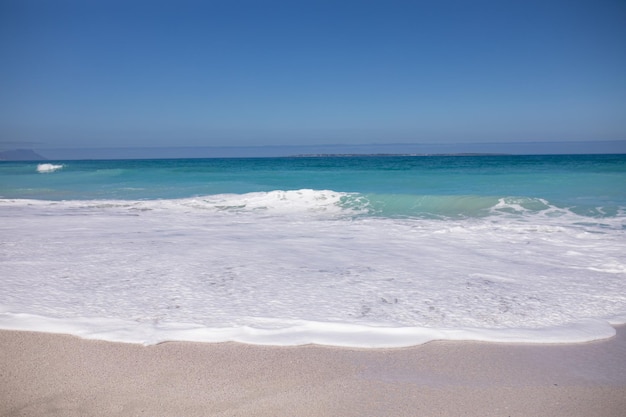 Vista de una playa de arena y un mar en calma con un cielo azul claro en un día soleado