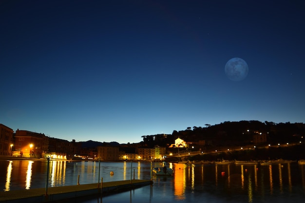 Vista de la playa Baia del Silenzio de noche con luces de luna llena y reflejos