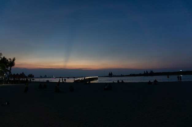 La vista de una playa durante la puesta de sol con un barco anclado a lo largo de la costa