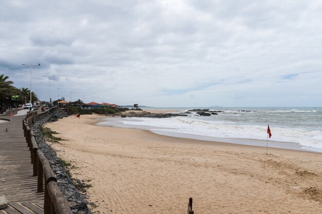 Vista de la playa de Rio das Ostras en Rio de Janeiro con cielo nublado y algunas nubes pesadas. Mar fuerte y arena amarillenta.