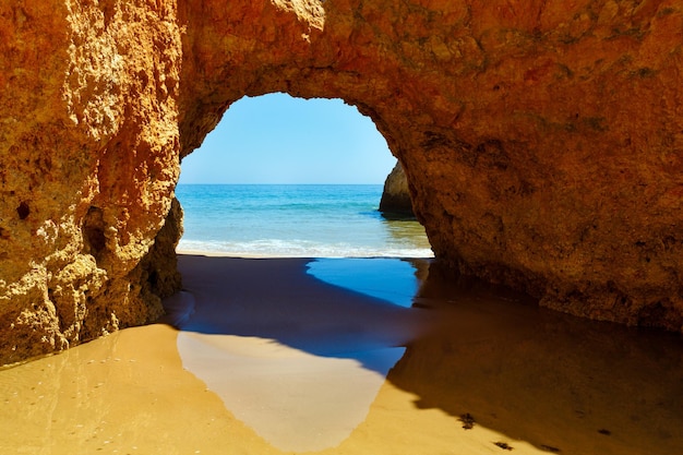 Vista desde la playa sobre el mar a través del arco rocoso (Dos Tres Irmaos, Portimao, Alvor, Algarve, Portugal).