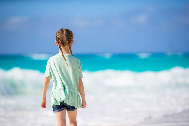 Vista posterior de la adorable niña en la playa