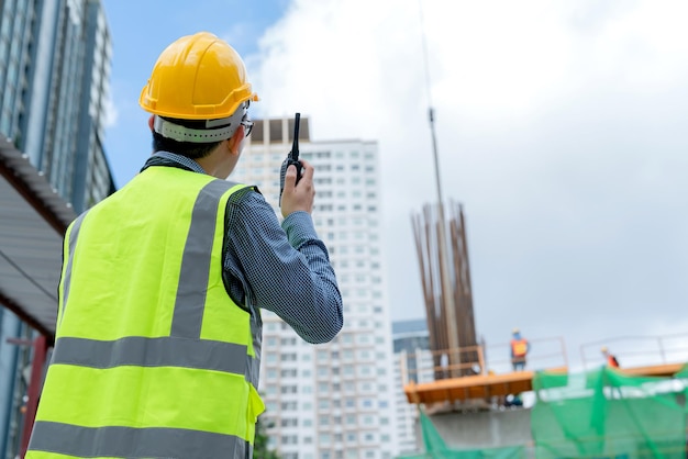 Vista posterior del casco de seguridad masculino asiático ingeniero profesional administrar el sitio de construcción de control con experiencia trabajando