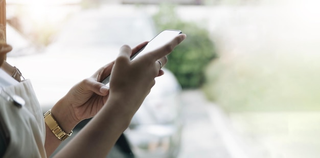 Vista posterior de cerca de una mano de mujer usando un teléfono inteligente con pantalla en blanco acostado en un sofá en casa