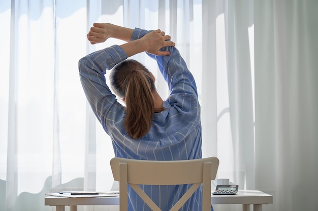 Vista posterior del dolor de espalda de estiramiento femenino debido al trabajo remoto aspectos negativos de trabajar en casa