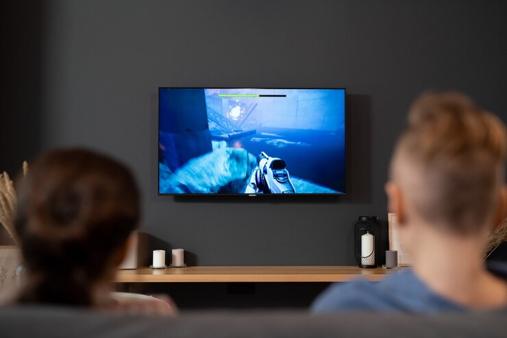 Foto vista posterior de dos hermanos contemporáneos sentados frente al televisor y jugando videojuegos en la sala de estar durante las vacaciones o los fines de semana