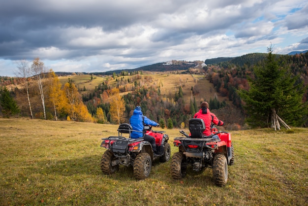 Vista posterior de dos hombres sentados en quads disfrutando del hermoso paisaje de montañas