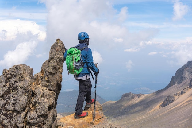 Vista posterior de un excursionista con una mochila verde en la cima del volcán Iztaccihuatl