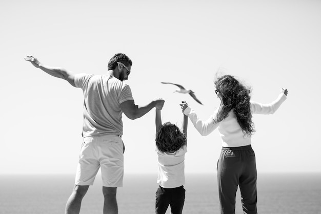 Vista posterior de la familia feliz en las vacaciones en la playa