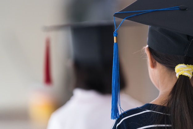 Vista posterior Los graduados de niños de la escuela femenina asiática con un gorro de graduación tienen un certificado enrollado. Concepto De Celebración De Graduación Foto de stock