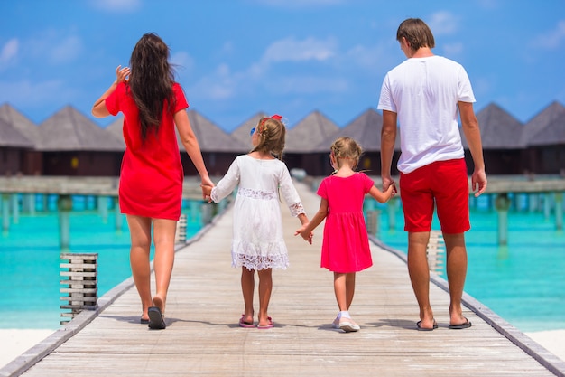 Vista posterior de una hermosa familia en un embarcadero de madera durante las vacaciones de verano en un resort de lujo