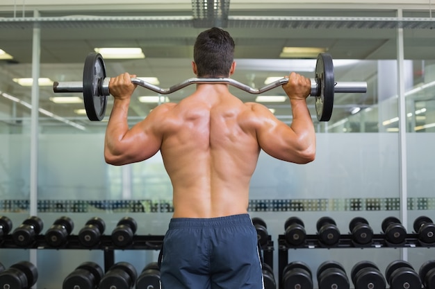 Vista posterior de un hombre musculoso levantando la barra