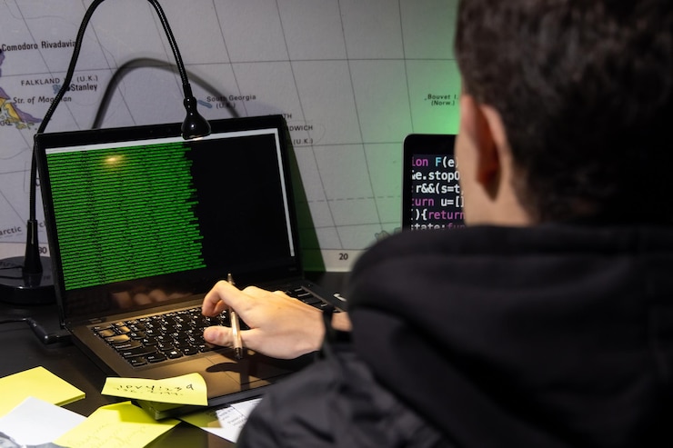 Foto vista posterior del hombre que planea un ataque de piratas informáticos. hombre con abrigo usando laptop, escribiendo código. hacking, tecnología, concepto de ciberdelincuencia