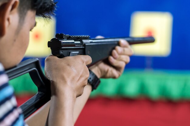 Vista posterior del hombre con su arma disparando al objetivo en la práctica Disparos