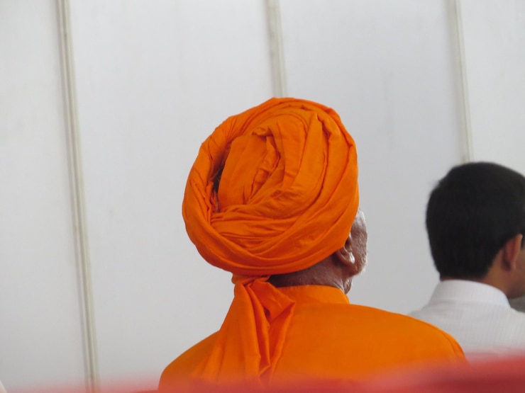 Foto vista posterior de un hombre con turbante naranja delante de una pared blanca