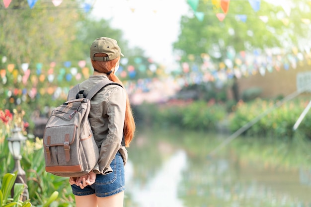 Vista posterior de una joven con mochila con mascarilla médica protectora contra covid19 De pie en el canal