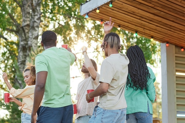 Vista posterior de jóvenes despreocupados bailando al aire libre en la fiesta de verano