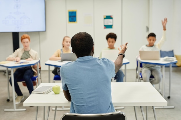 Vista posterior de una maestra afroamericana trabajando con un grupo diverso de niños, copiando espacio