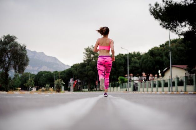 Foto vista posterior de la mujer corriendo por la carretera en la mañana