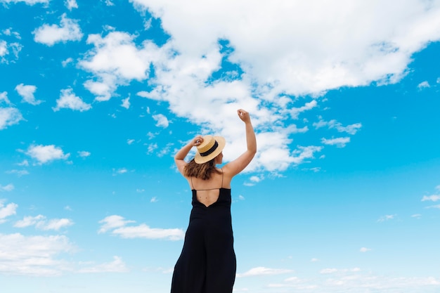 Vista posterior de la mujer disfrutando de la libertad al aire libre con cielo y nubes