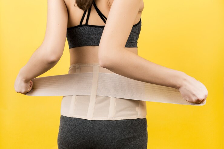 Foto vista posterior de la mujer embarazada vistiendo un corsé ortopédico para que el dolor de espalda desaparezca en la superficie amarilla con espacio de copia