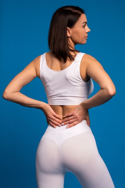 Vista posterior de la mujer en forma en ropa deportiva blanca sobre pared azul