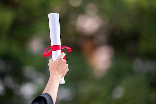 Vista posterior de una mujer graduada con un título universitario con un diploma