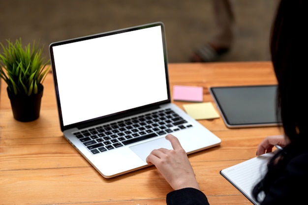 Vista posterior de una mujer de negocios que trabaja con una pantalla blanca en blanco de la computadora portátil en la oficina.