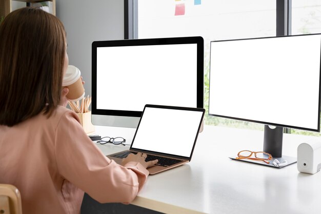 Vista posterior de la mujer que trabaja con la computadora portátil en el lugar de trabajo moderno.