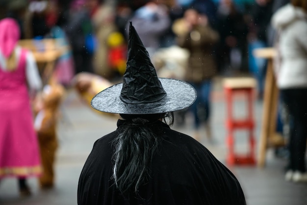Vista posterior de una mujer con un sombrero de bruja en el carnaval de disfraces
